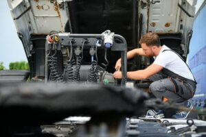truck maintenance failures A mechanic in overalls works on a truck engine