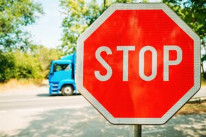 stop sign (1) Red stop sign beside a roadway with a blue truck passing in the background
